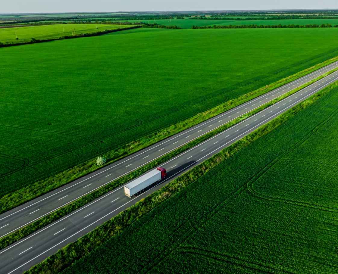 lorry driving on road with green fields